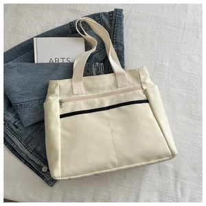 Dettaglio della borsa tote in tela color crema con tasche funzionali e chiusura a zip