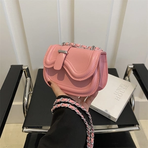 Pink mini crossbody bag with wave flap design and silver chain strap shown in a hand