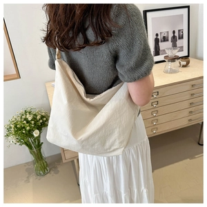 Close-up of a large beige pleated nylon hobo bag with silver zipper and wrinkled texture