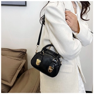 Detail of a black oil wax leather Boston bag with gold metal buckle on a white blazer