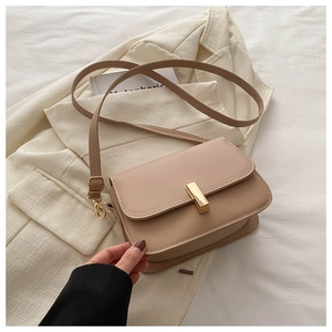 Detail of beige faux leather crossbody bag with a polished gold rectangular metal buckle