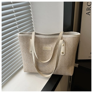 Close-up of beige woven texture and leather straps with gold rivets on tote bag