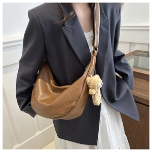 Detail view of brown vintage half-moon crossbody bag with cute plush bear pendant