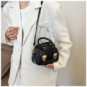Detail shot of a mini black pillow bag with gold hardware and a slim leather shoulder strap