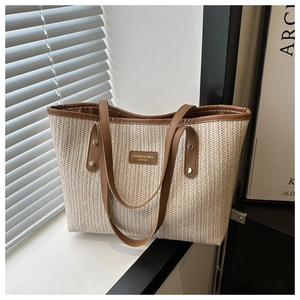 Macro detail of V-shaped woven tote bag with brown leather trim and golden rivets