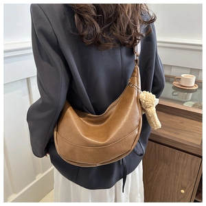 Brown vintage half-moon shoulder bag with a cute plush bear charm on the strap