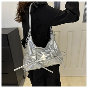 Detail of silver metallic pleated bag featuring dual bow accents and chic chain strap