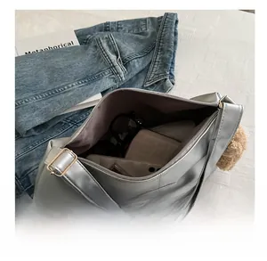 Spacious interior of silver metallic crossbody bag holding sunglasses and wallet