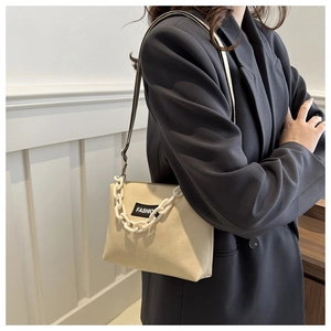 Détail du sac à bandoulière crème avec grosse chaîne et étiquette de mode