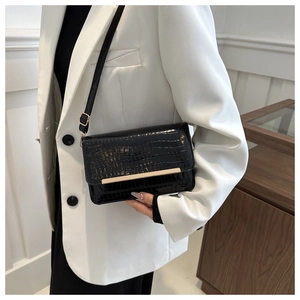 Detail of black crocodile texture bag with gold hardware and flap closure for women