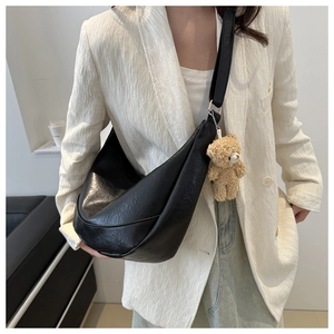 Detailed close-up of a black hobo shoulder bag with a cute plush bear charm accessory