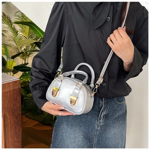 Detail of silver metallic Boston bag with golden buckles and dual handles