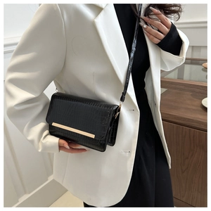 Detailed view of crocodile pattern crossbody bag with minimalist gold metal bar trim