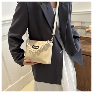 Détail du sac bandoulière beige minimaliste avec étiquette mode et chaîne décorative