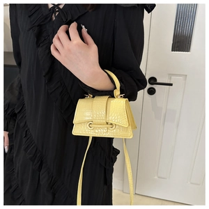 Detail of yellow crocodile pattern mini handbag with handle and crossbody strap