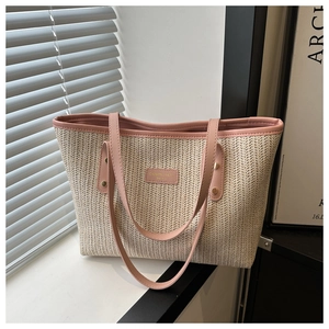 Detail of beige woven tote bag with pink leather handles and gold metal rivets