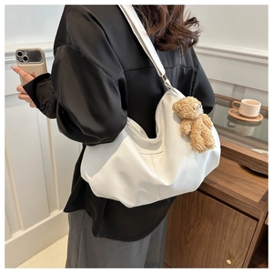 Detail of white PU leather tote bag with soft pleats and a cute brown plush bear charm