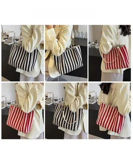 Detailansicht der gestreiften Canvas-Tote Bag mit Goldkette an einem Model im Café