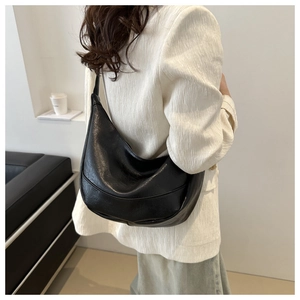 Close-up of black glossy hobo bag showing natural leather texture and crescent shape