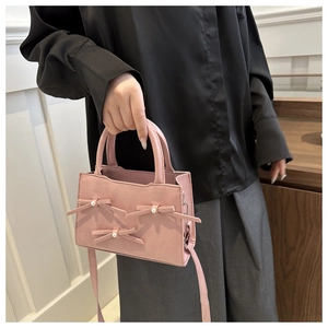 Dettaglio borsa in ecopelle rosa con tre fiocchi 3D e decorazioni in perle bianche