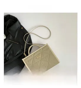 Detail view of khaki quilted handbag showing chic diamond stitching and golden logo plate