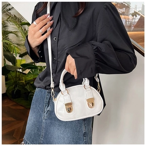 Close-up of a white leather mini Boston bag featuring elegant golden metal locks and handle