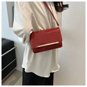 Detail of red crocodile pattern shoulder bag with sleek metal trim and leather texture