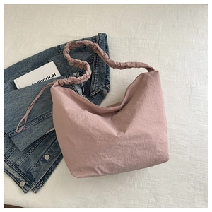 Detailed view of pink pleated hobo bag with scrunched strap on denim jacket