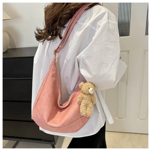 Detailed side view of pink faux leather hobo shoulder bag with cute teddy bear charm