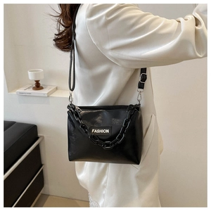 Detail of black crossbody bag with matte thick chain and white fashion woven label