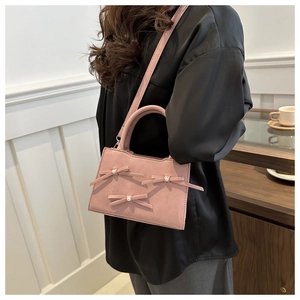 Borsa a mano rosa con fiocchi di perle e tracolla sottile in finitura opaca chic