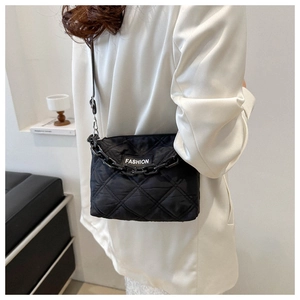 Dettaglio borsa shopper trapuntata nera con etichetta moda e catena su blazer bianco