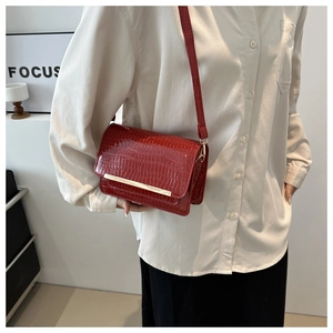 Detail of red crocodile texture flap crossbody bag with elegant gold metal trim