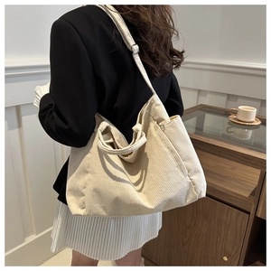 Close-up of a large beige corduroy tote bag with dual handles and adjustable shoulder strap