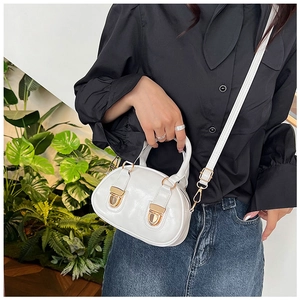 Close-up of white mini Boston bag with gold buckles and glossy oil wax leather finish