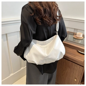 Detail of white pleated cloud tote bag with minimalist logo patch on a female model