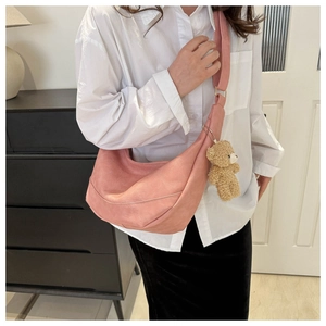 Detailed shot of a pink hobo shoulder bag featuring a cute brown plush bear charm