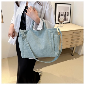 Detail view of light blue corduroy tote bag showing textured fabric and side pocket