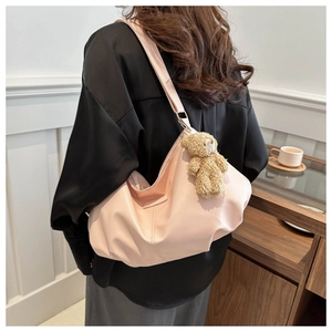Detail of pink puffy tote bag with teddy bear pendant shown on model in a cafe