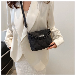 Dettaglio della borsa trapuntata nera con catena e etichetta fashion su modella in blazer