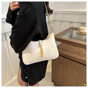 Detail of white faux leather shoulder bag with gold hardware and chain strap