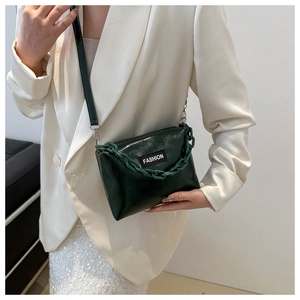 Detail view of dark green glossy crossbody bag with thick acrylic chain and fashion label