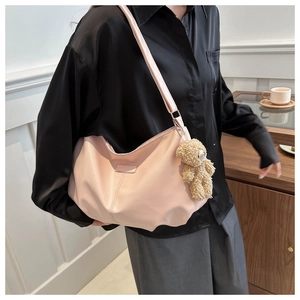 Detail of soft pink dumpling bag with matte leather texture and cute bear charm