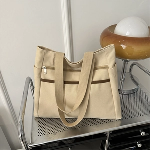 Borsa tote minimalista in tela beige con strisce marroni su un carrello mobile