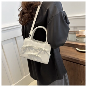 Borsa a tracolla bianca in pelle con perle e fiocchi indossata da una modella