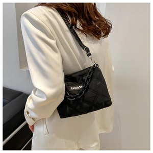 Dettaglio della borsa tote trapuntata nera con etichetta FASHION e tracolla a catena su modella