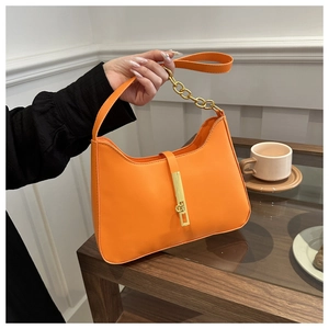 Detail of orange minimalist shoulder bag with gold chain strap and metallic lock clasp