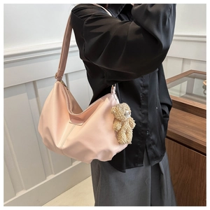 Close-up of pink nylon tote bag featuring a cute plush bear charm and wide shoulder strap