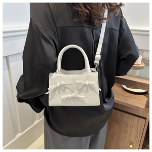 Dettaglio mini borsa bianca con fiocchi di perle, tracolla regolabile e texture in pelle
