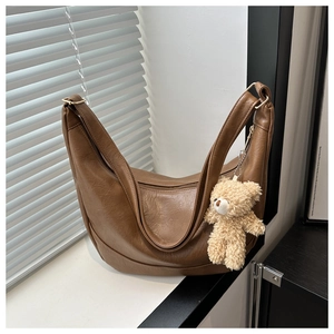 Detail of brown crescent shoulder bag with soft PU texture and cute plush bear charm